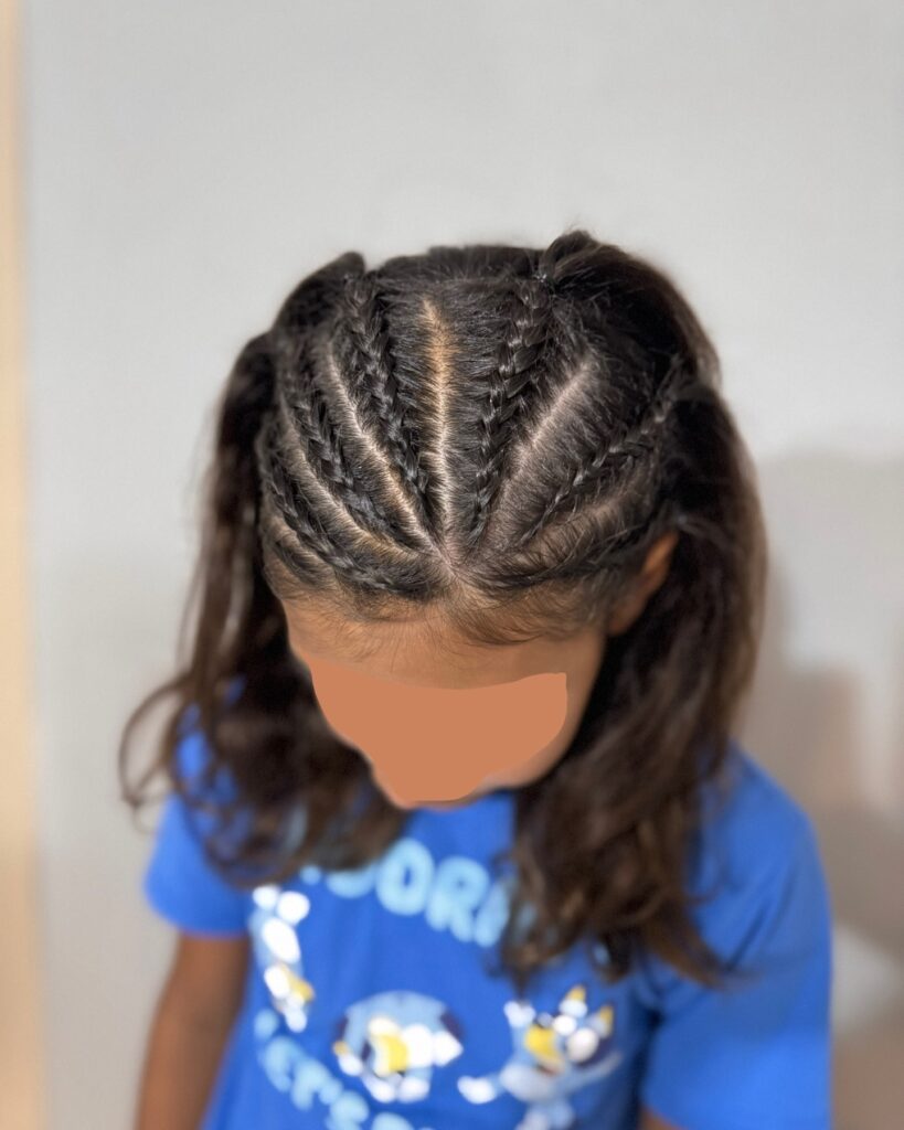 Small Dutch braids on dark brunette hair styled into a half up hairstyle with loose waves.