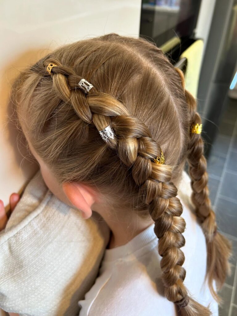 Chunky blonde Dutch braids with gold braid cuffs styled on long smooth hair.