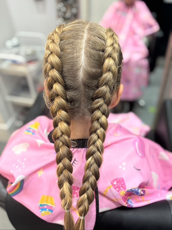 Two classic long Dutch braids on blonde hair with a clean center part.