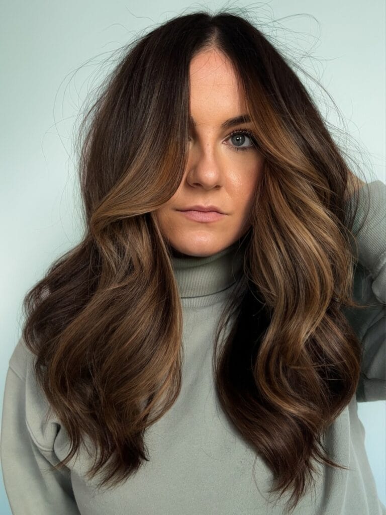 Long wavy brunette hair with face framing highlights and soft volume.