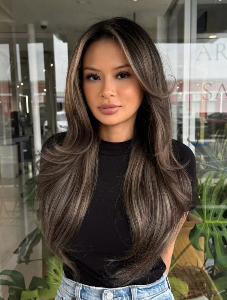 Long brunette hair with glossy waves and multi tonal highlights.