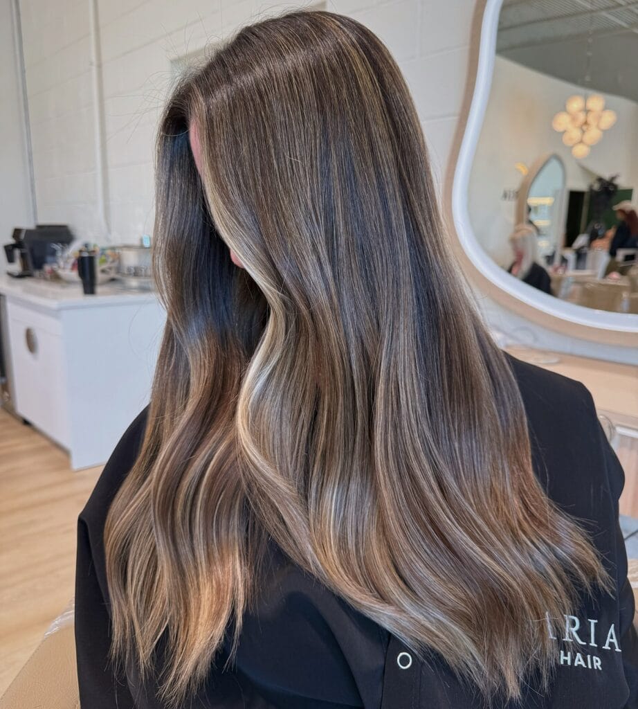 Long brunette hair with soft waves and cool toned ash brown highlights.
