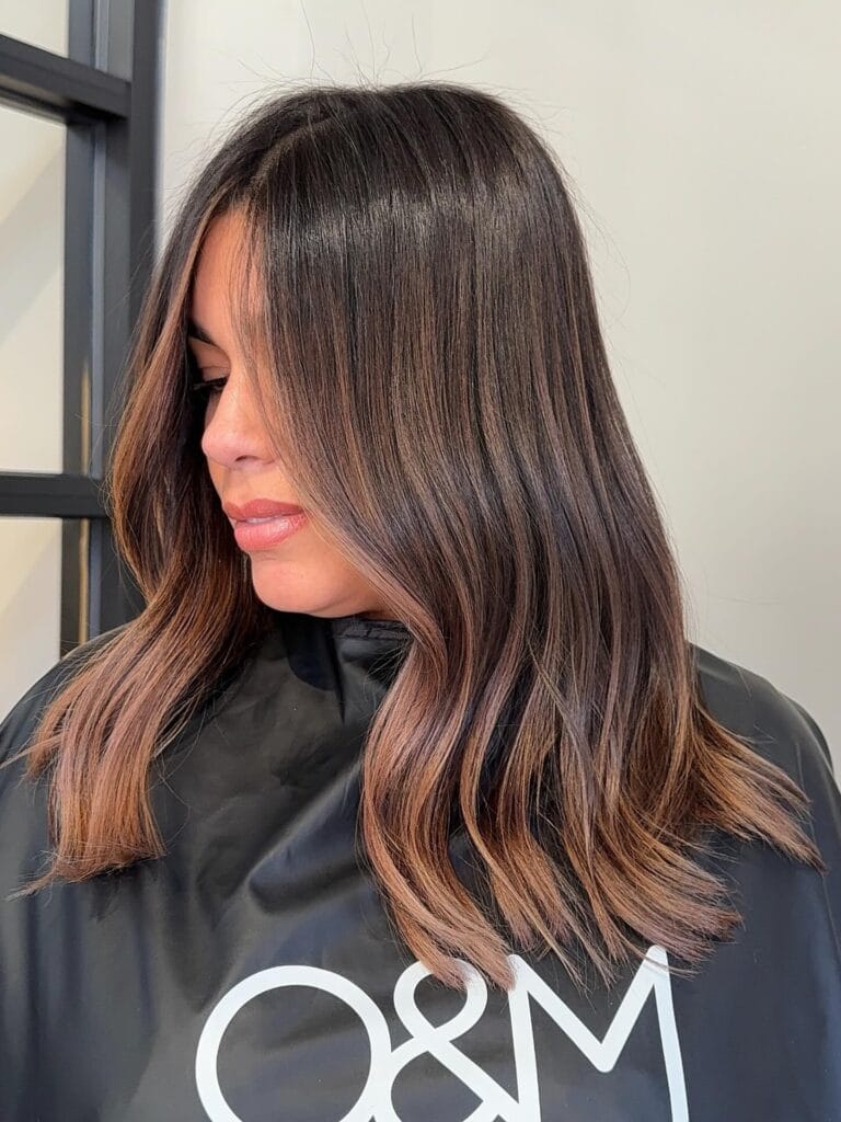 Shoulder length brunette hair with soft waves and warm caramel highlights.