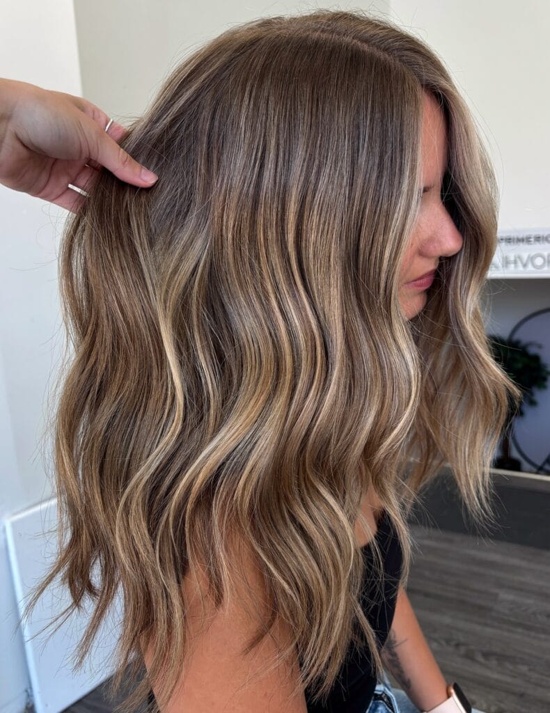 Medium length wavy brunette hair with beige balayage highlights.
