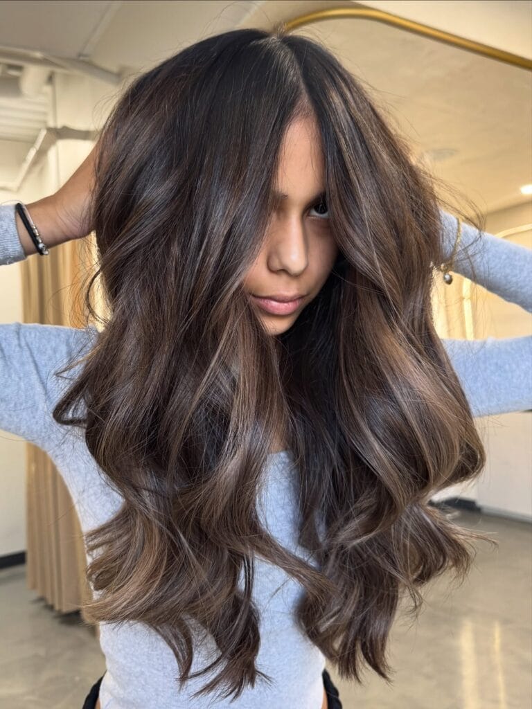 Long layered brunette hair with soft waves and subtle chocolate highlights.