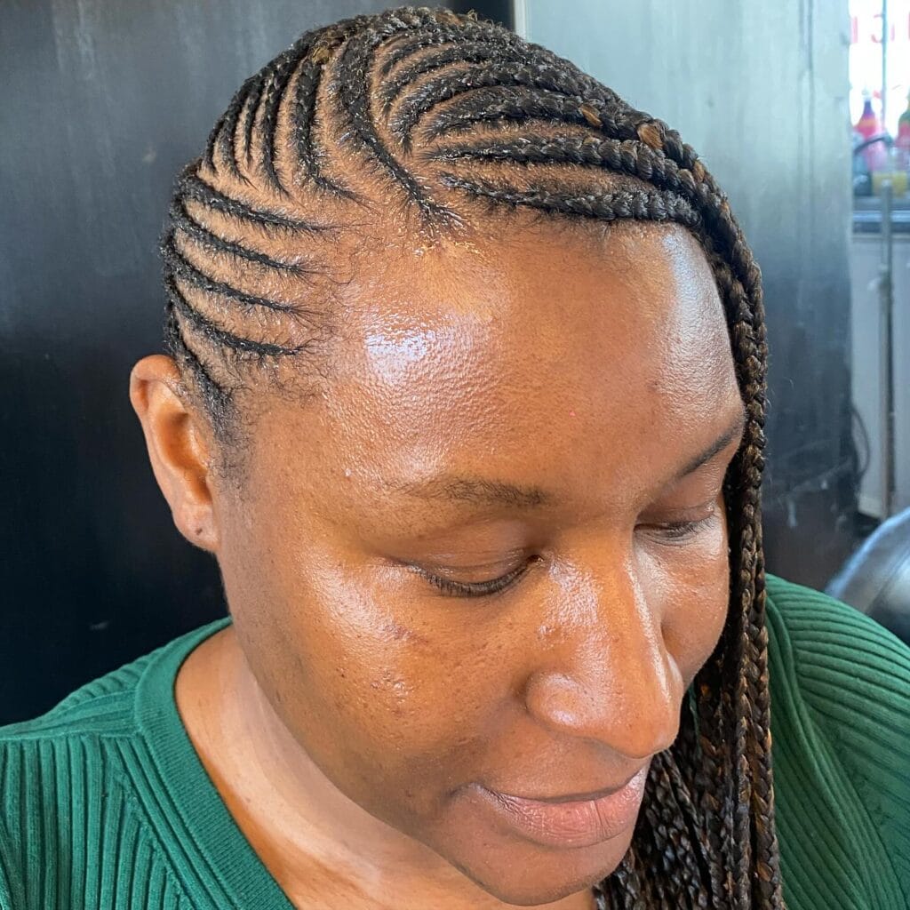Curved cornrow braids styled to one side and continuing into long braids.