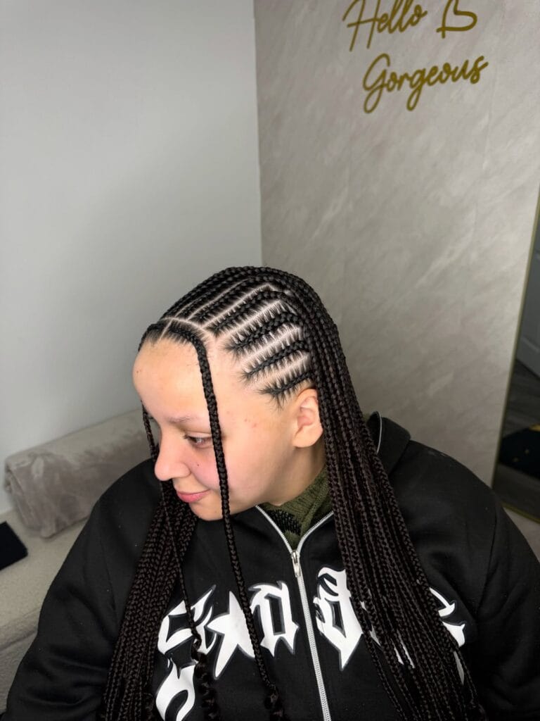 Side parted cornrows braided into long sleek braids flowing down the shoulders.