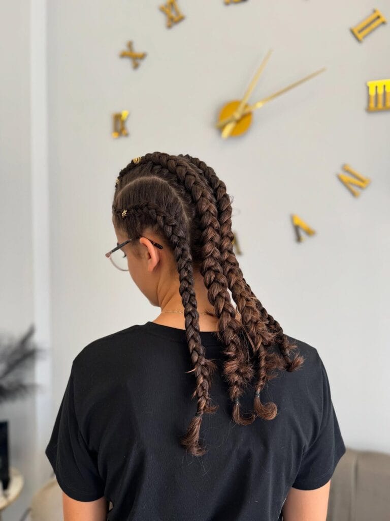 Two French braids with loose curly ends styled for a sporty look.