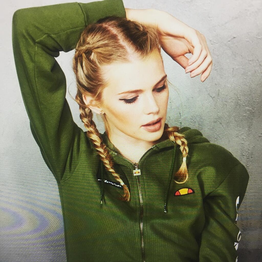 Two braided pigtails parted down the middle for a sporty hairstyle.