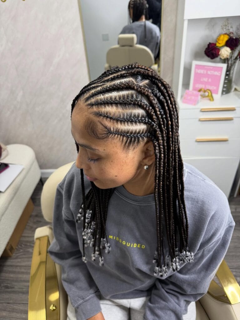 Curved cornrow pattern flowing into shoulder length braids.
