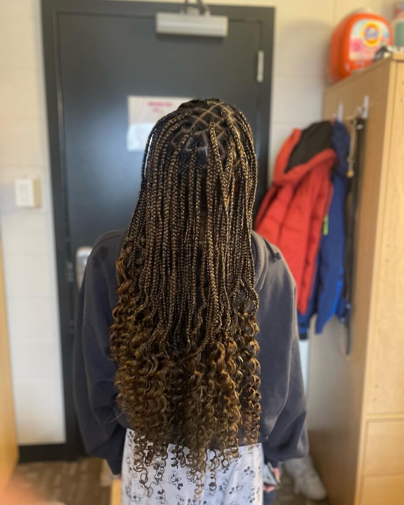 Medium length brown boho braids with curly ends and subtle caramel highlights.