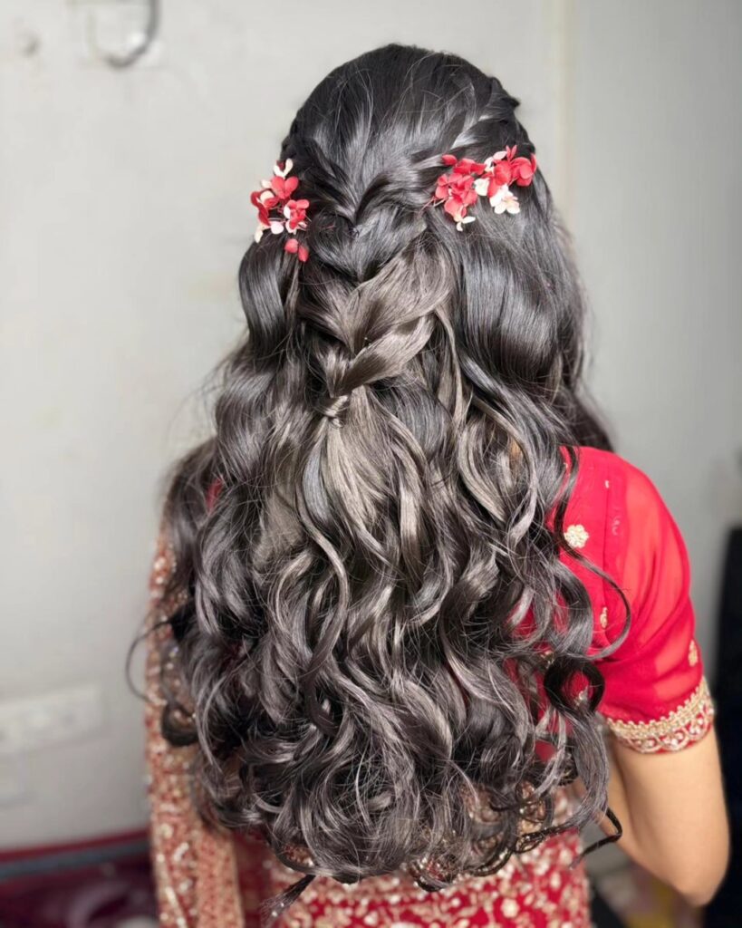 Long black wavy hairstyle with a braided crown and red floral hair accessories.
