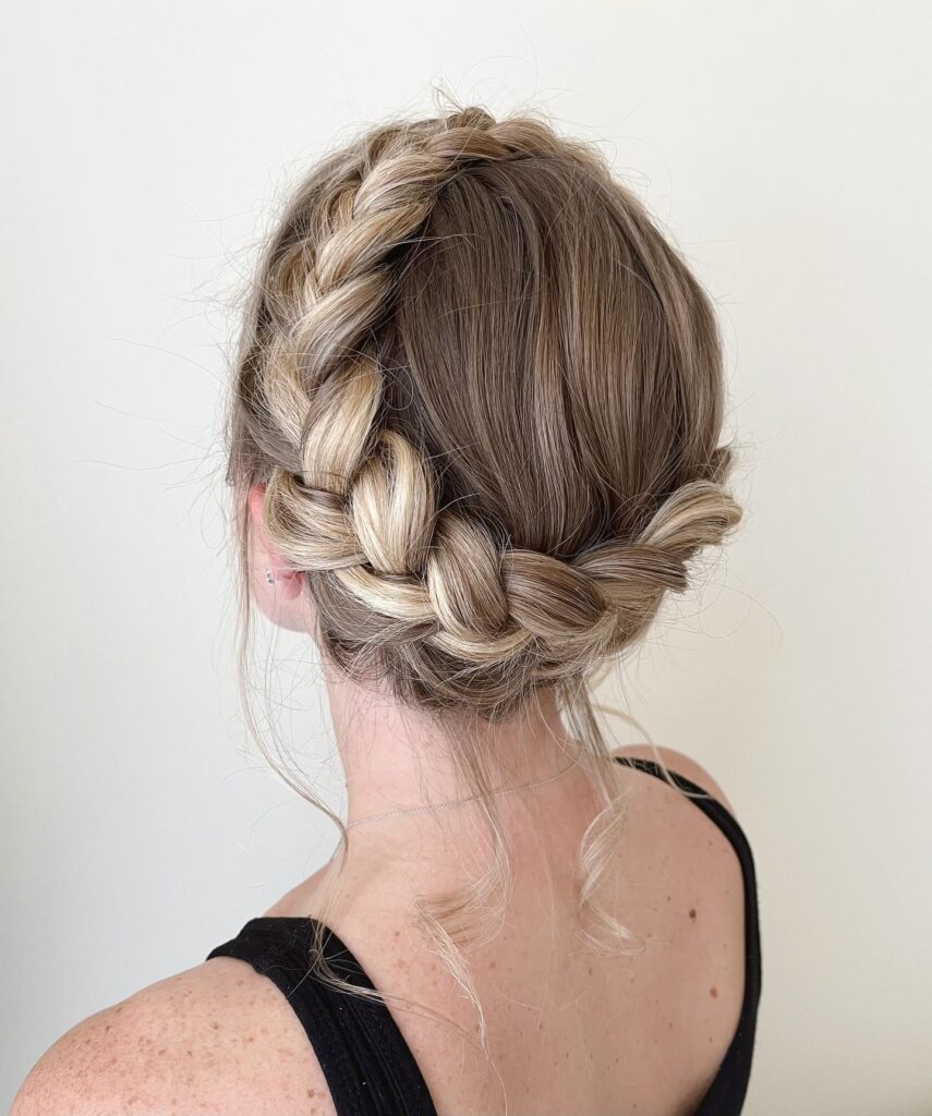 Ash blonde braided crown updo with a thick side braid and loose curled strands.