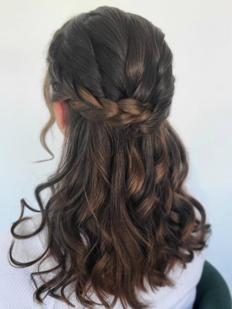 Brunette half up hairstyle with twisted crown sections and loose curls.