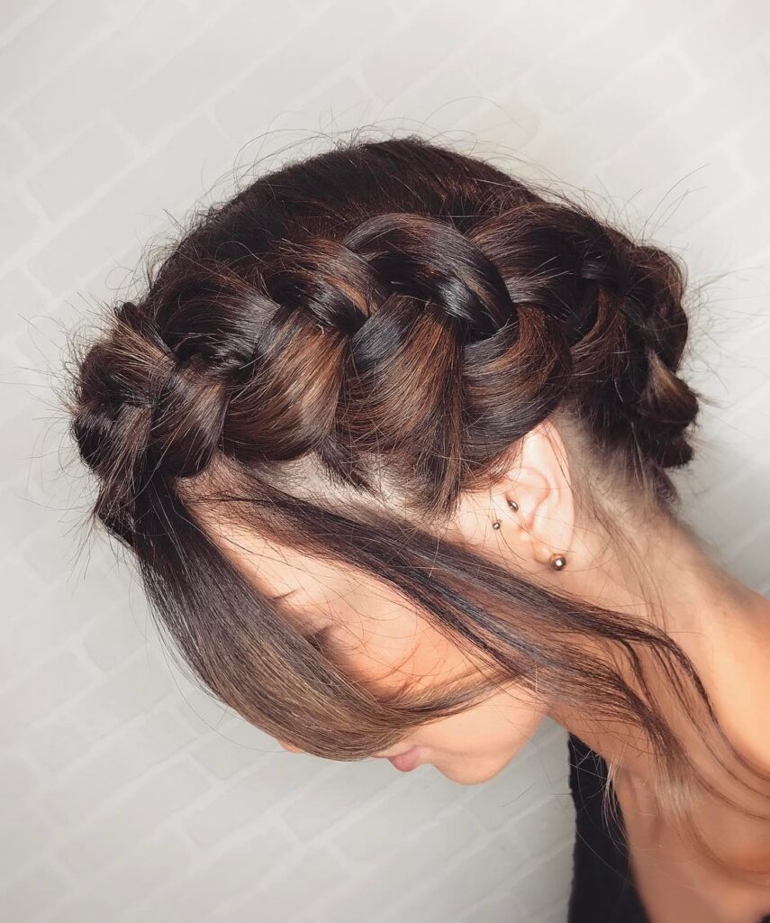 Dark brunette halo braid updo with thick woven braids and soft side bangs.