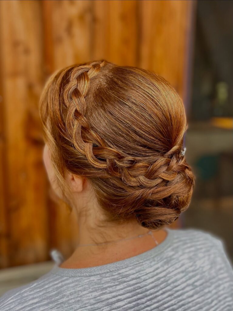 Brunette braided crown hairstyle with a sleek low bun and side braid detail.