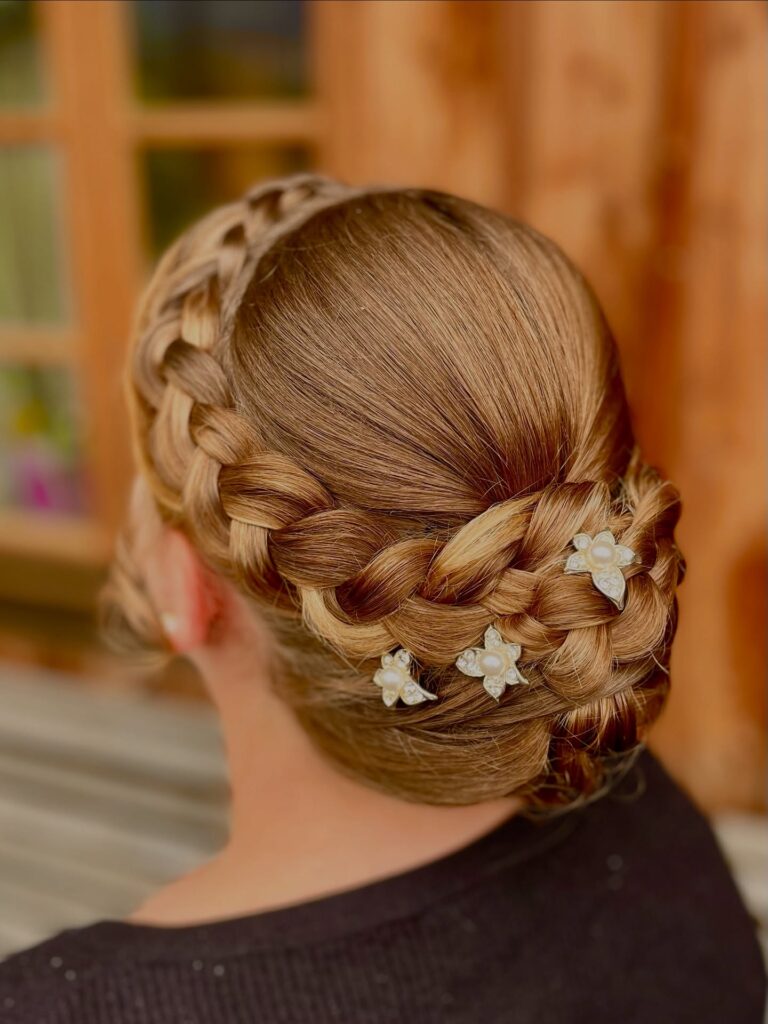 Sleek blonde braided crown bun hairstyle with pearl floral hair accessories.