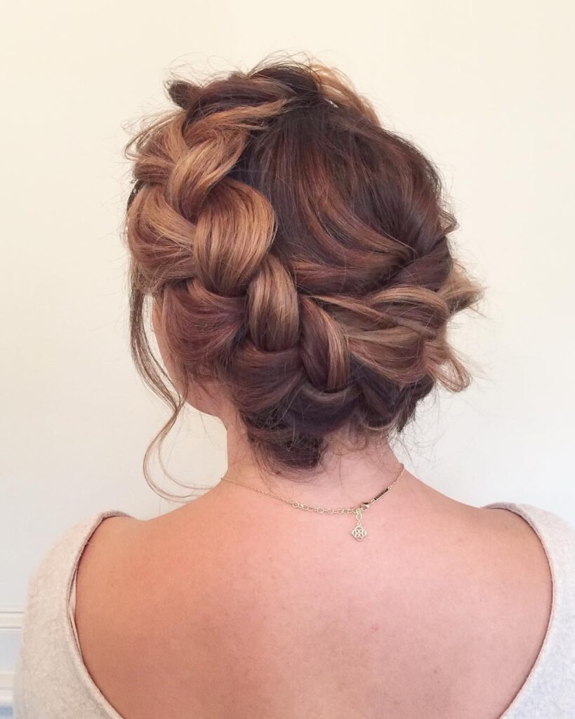 Loose copper brown braided crown bun hairstyle with soft face framing strands.
