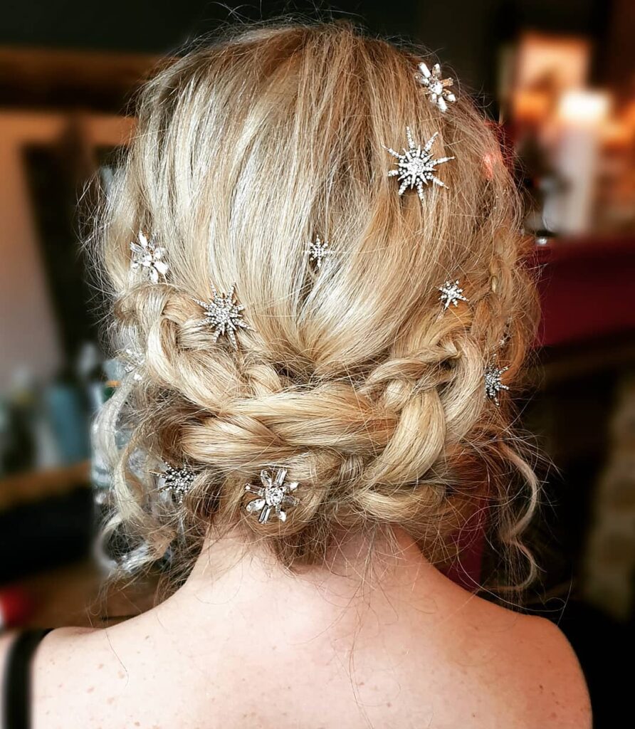 Blonde braided crown updo with loose curls and sparkling star hair accessories.