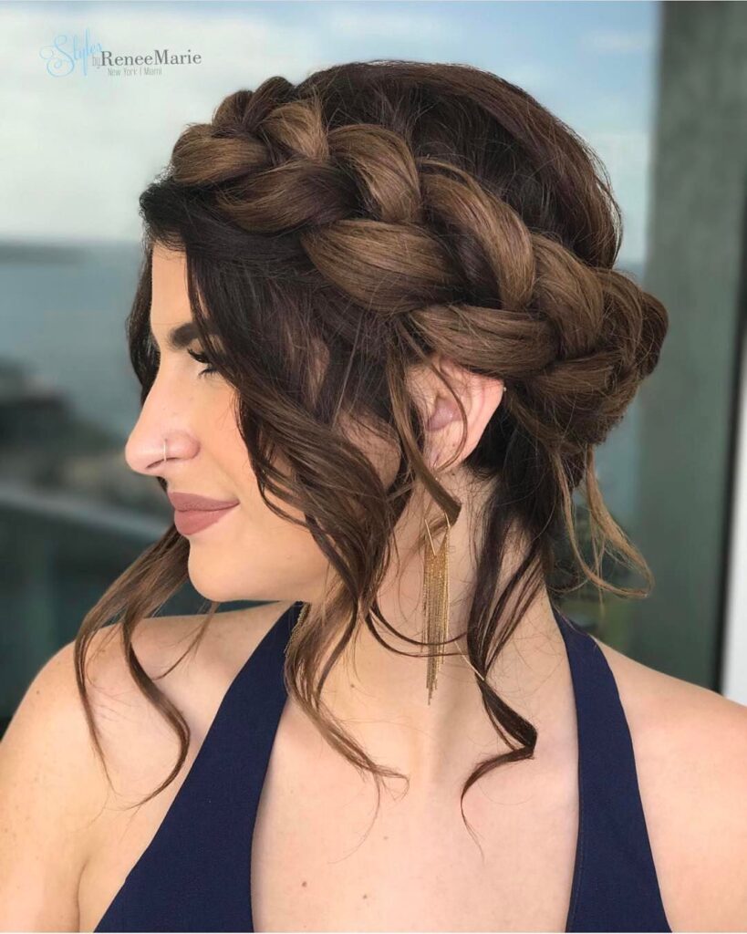 Brunette braided crown updo with loose curled strands around the face.