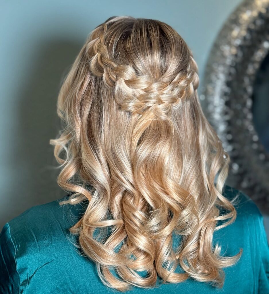Soft blonde crown braid hairstyle with loose curls and braided details across the back.