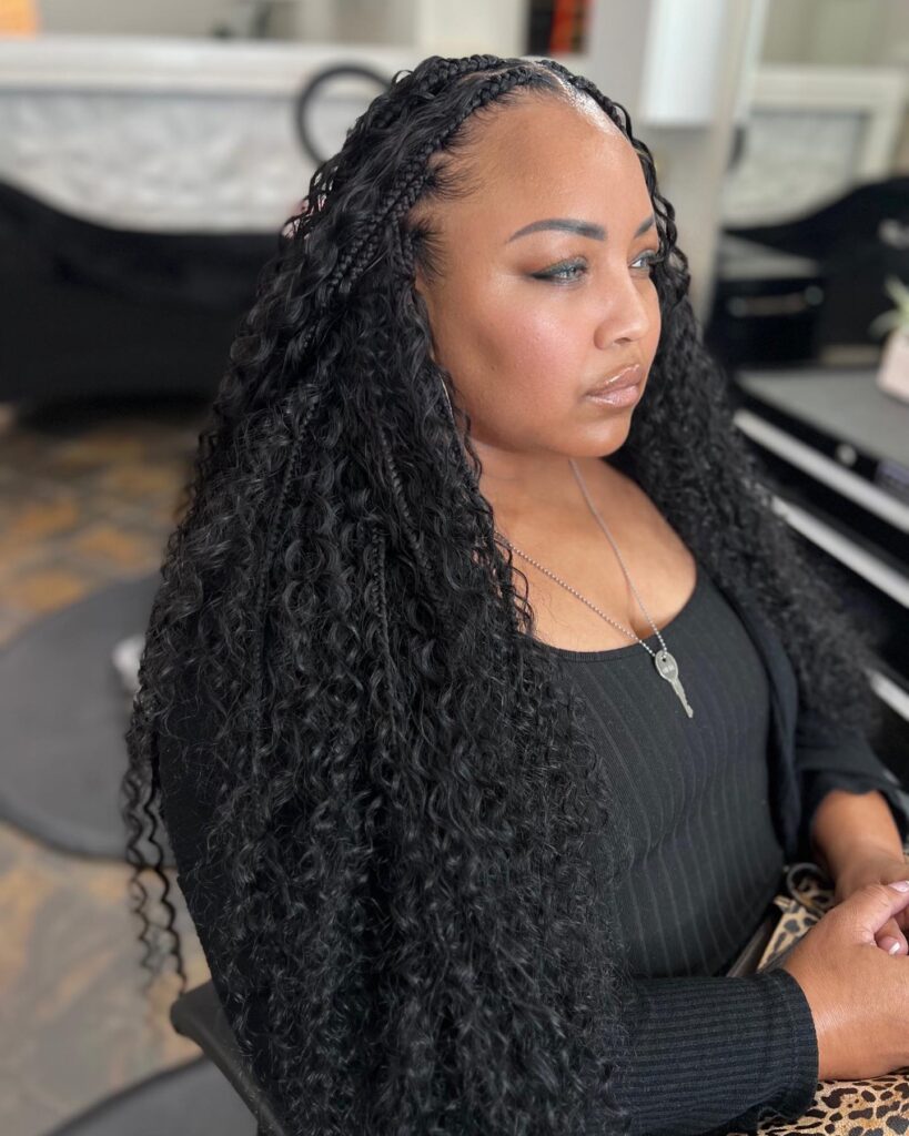 Black island braids with small cornrow sections at the front and long loose curly lengths.