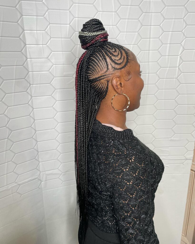 Long braided mohawk with cornrow base and a top knot accent.