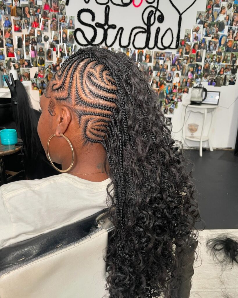 Braided mohawk with intricate swirl cornrows and long curly extensions.