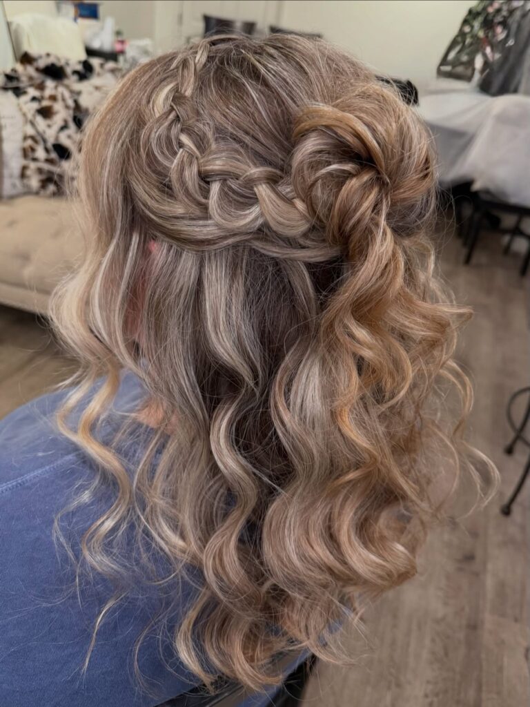 Ash blonde hair styled in loose curls with a side braid and rosette half up detail.