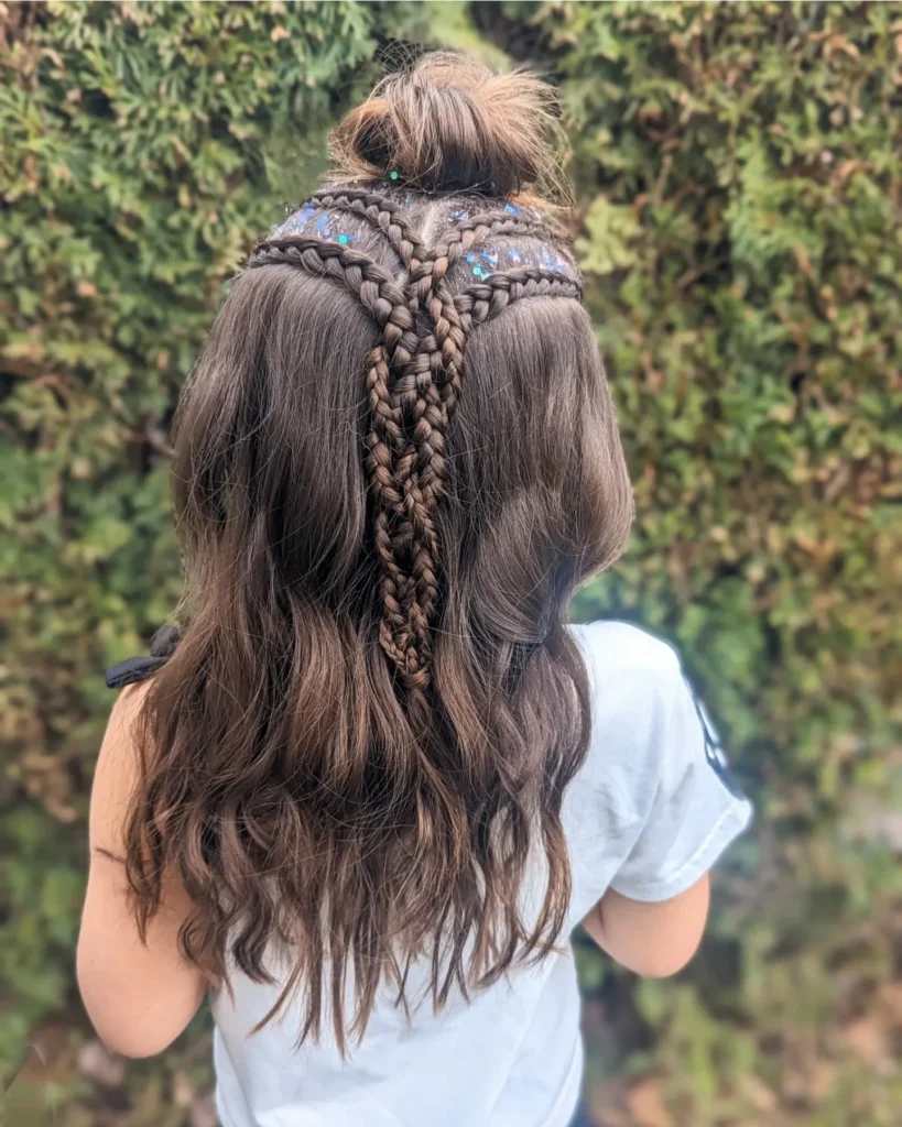 Long dark brown hair styled in a half up hairstyle with multiple detailed braids and loose waves.