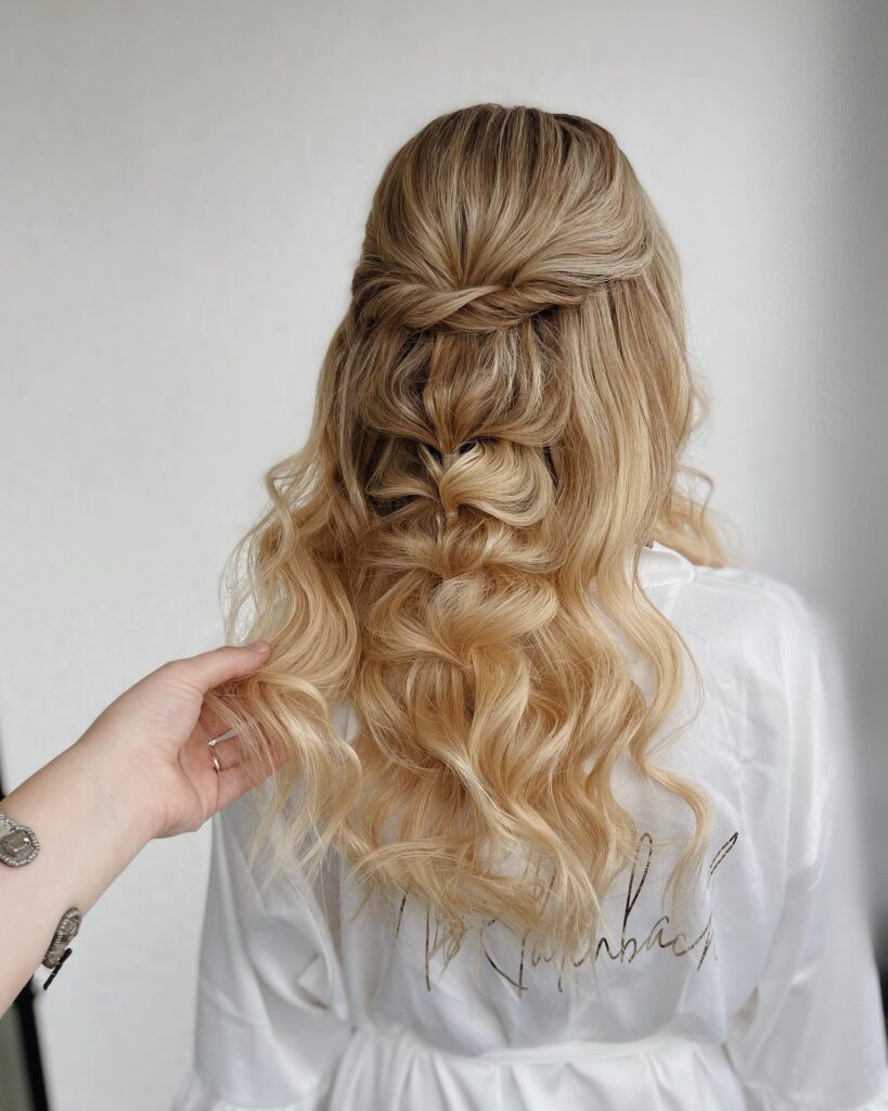 Blonde wavy hair styled in a half up hairstyle with a twisted crown and bubble braid.