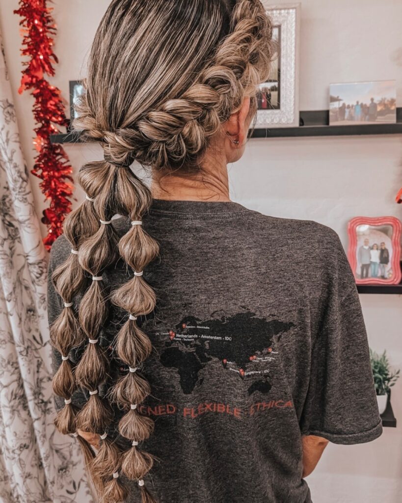 Side Dutch braid leading into a long bubble ponytail with evenly spaced sections.