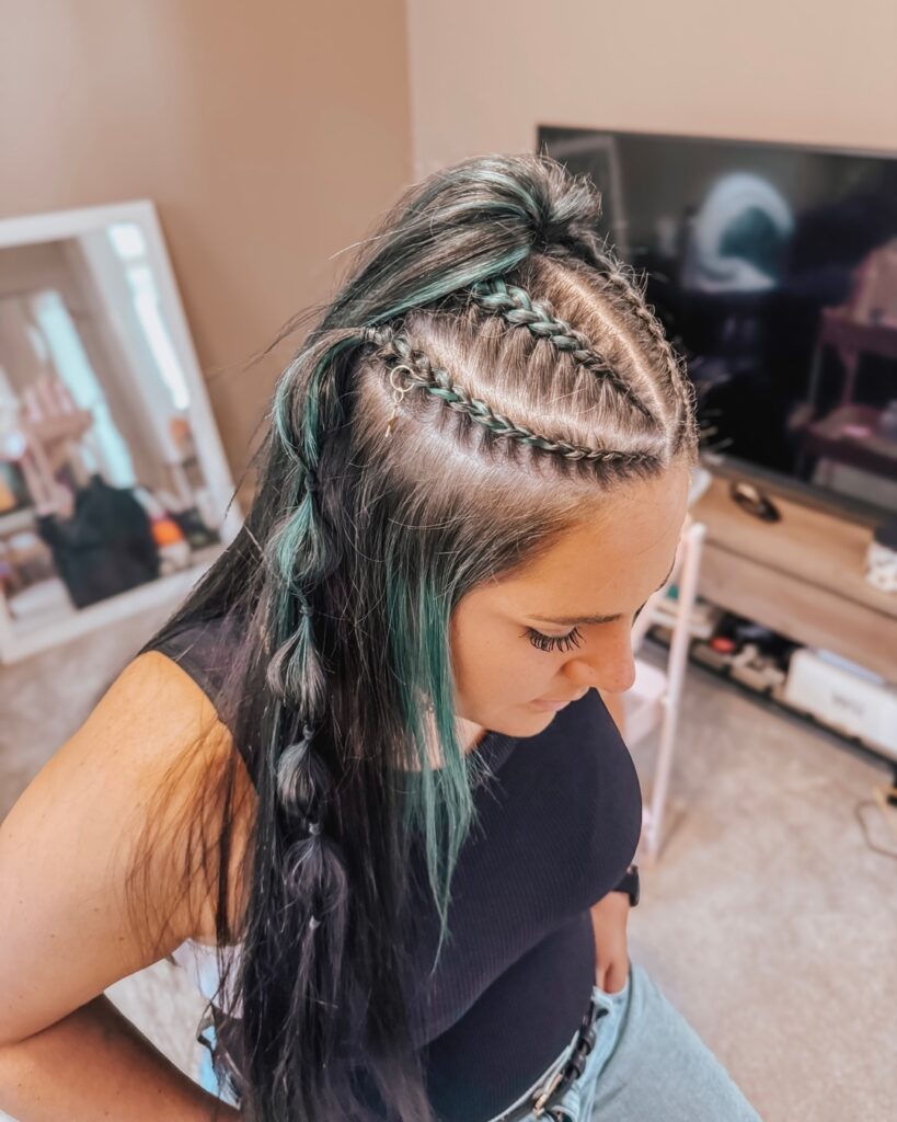 Side cornrow braids with long straight hair and teal highlight streaks.