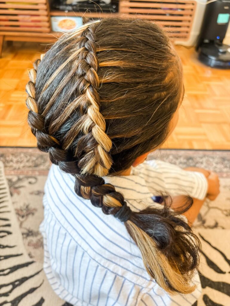 Two Dutch braids leading into a low bubble ponytail with tied sections.