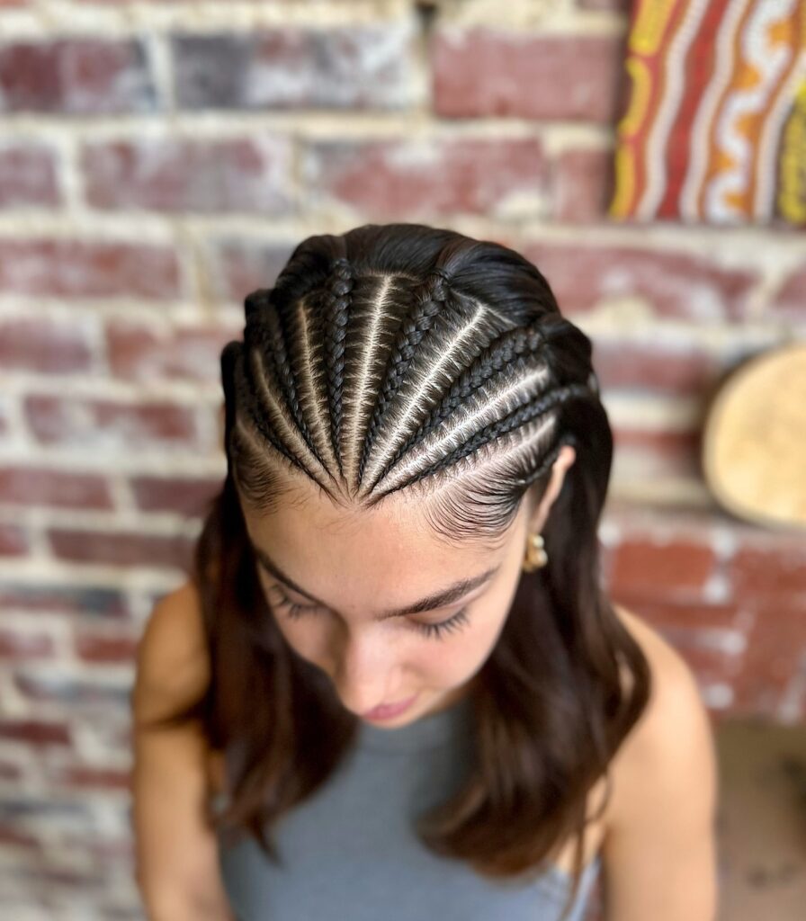 Fan shaped cornrows at the front blending into soft wavy shoulder length hair.