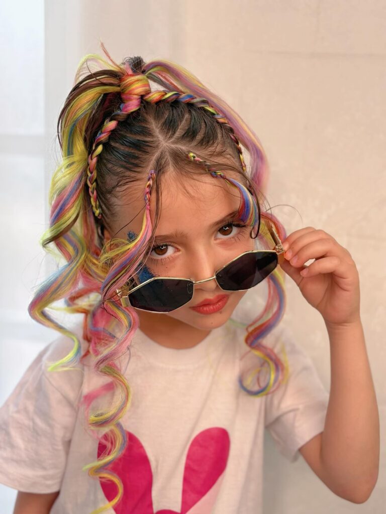 High braided ponytail with rainbow colored strands and loose curled ends.