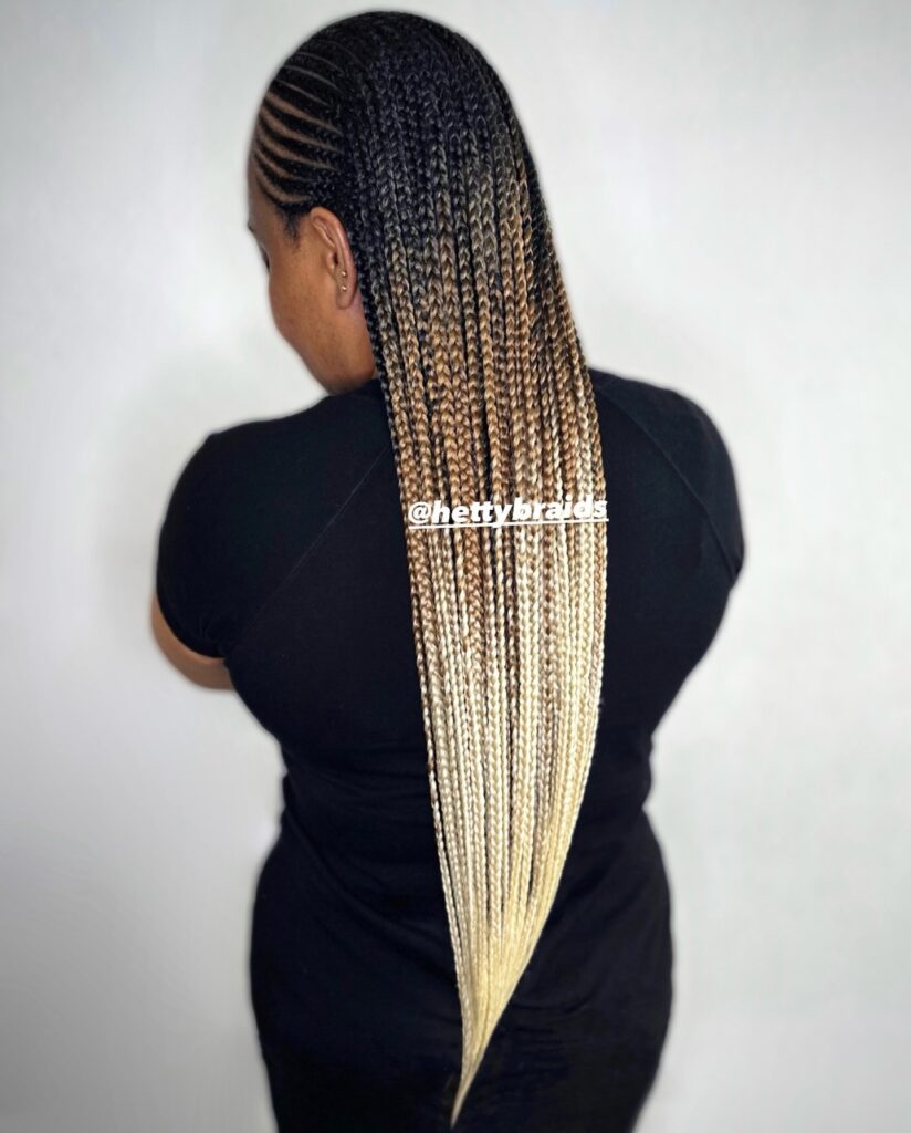 Long knotless braids with dark roots fading into blonde ends and neat side cornrow detailing.
