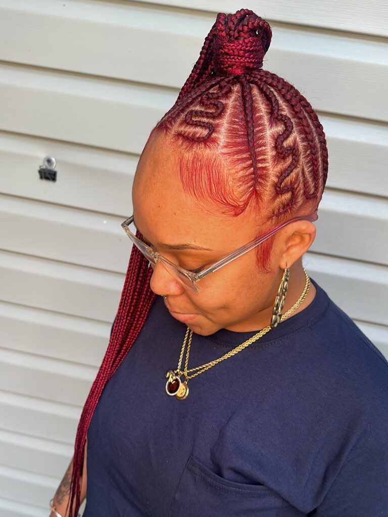 Burgundy braided top knot with detailed swirl cornrow patterns on the scalp.