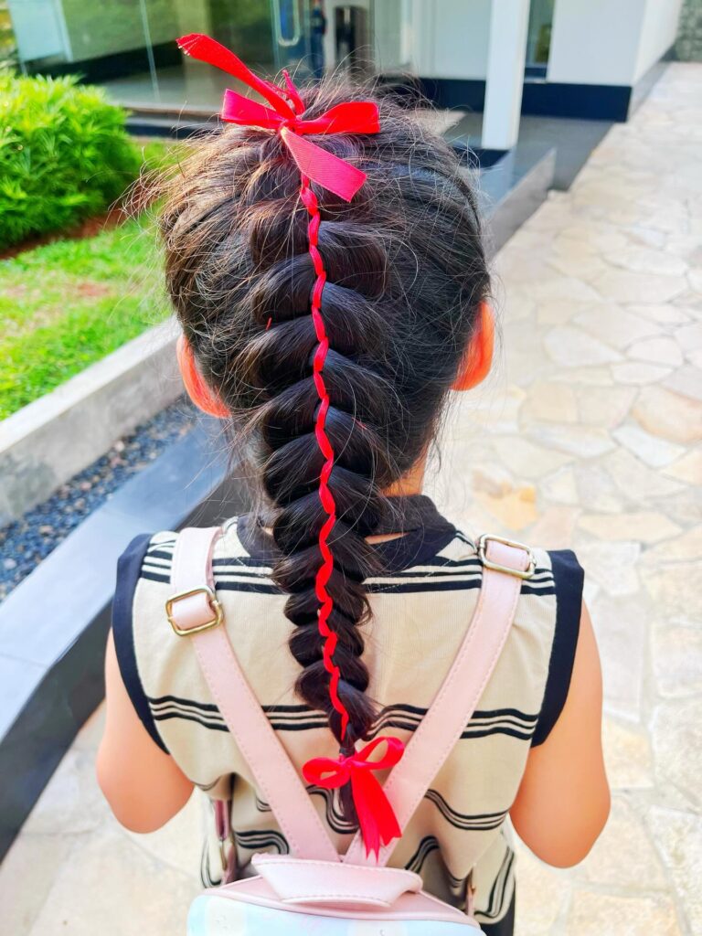 Thick bubble braid with a red ribbon woven through and bows at the top and bottom.