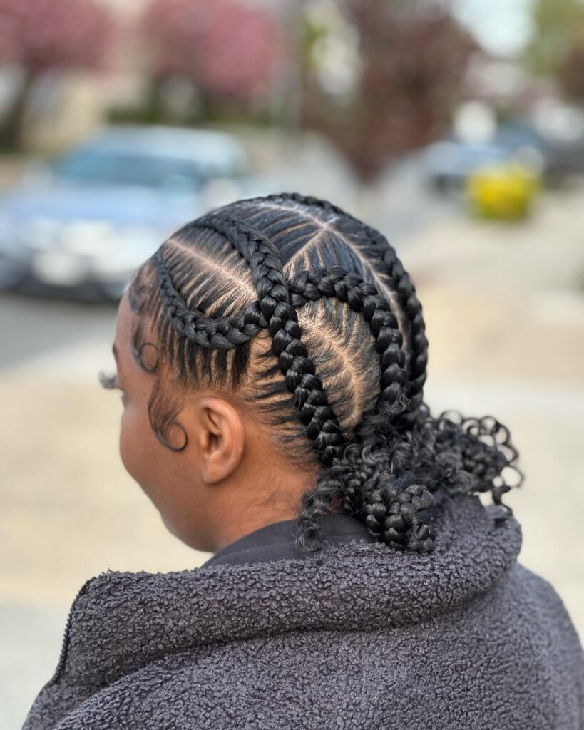 Criss cross cornrow braids leading into a ponytail with curly ends.