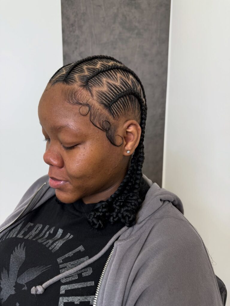 Curved cornrows with styled baby hairs and braids gathered toward the back.