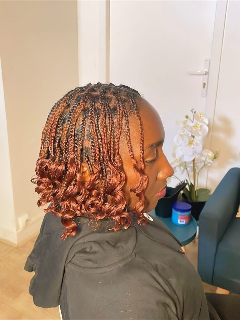 Short copper knotless braids styled into a bob with defined curly ends.