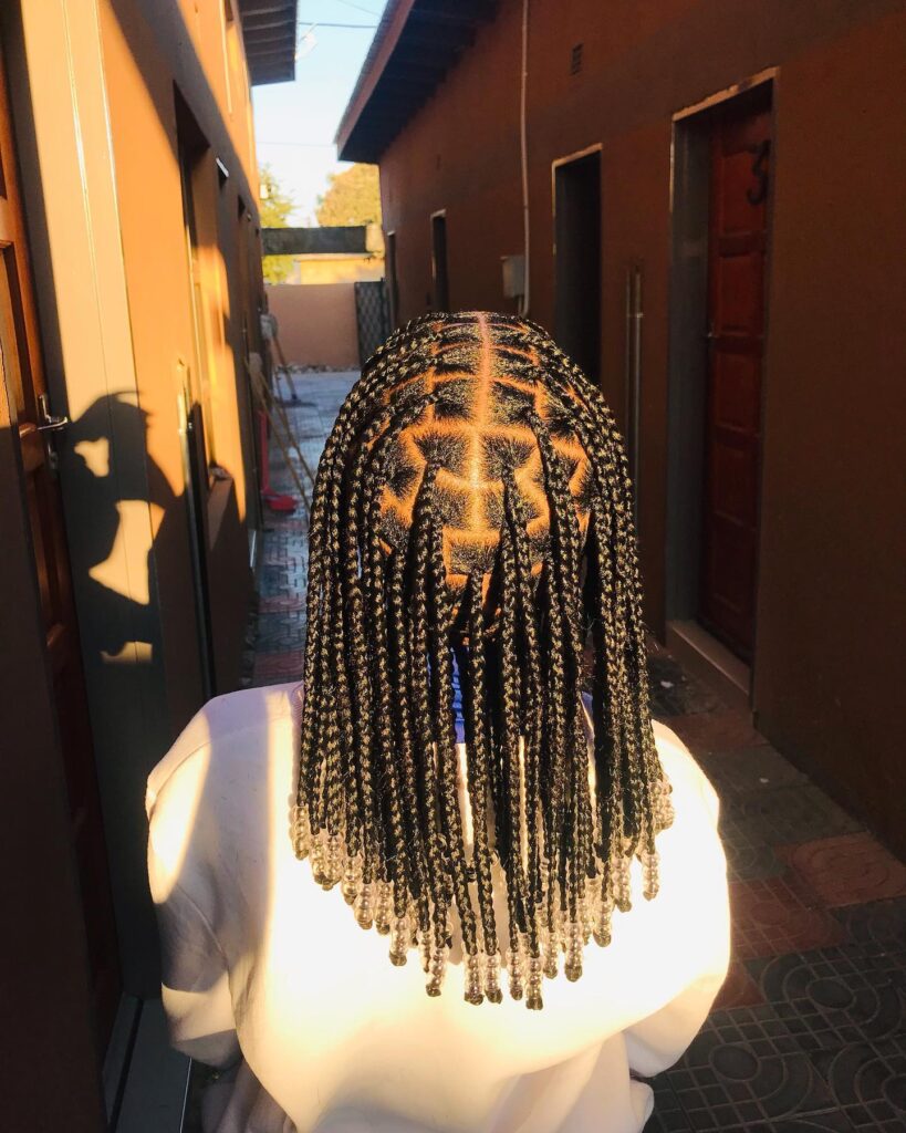 Black box braids with geometric parting and clear beads on the ends.