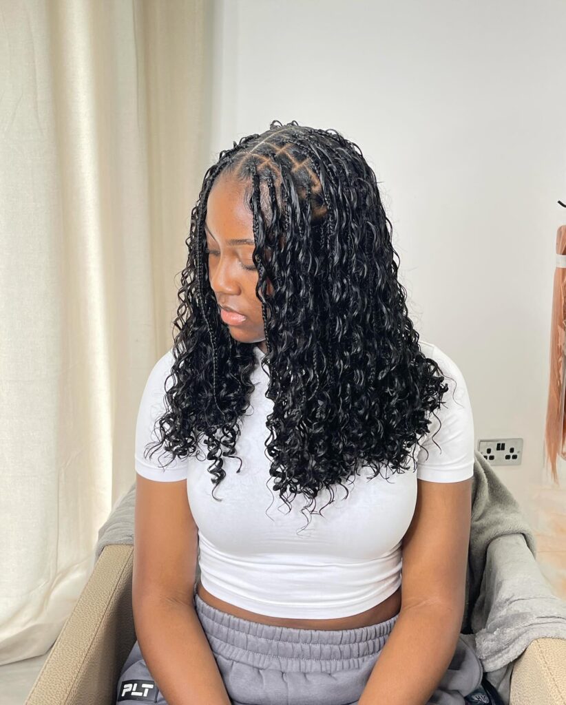 Shoulder length knotless braids with a middle part and soft curly ends.
