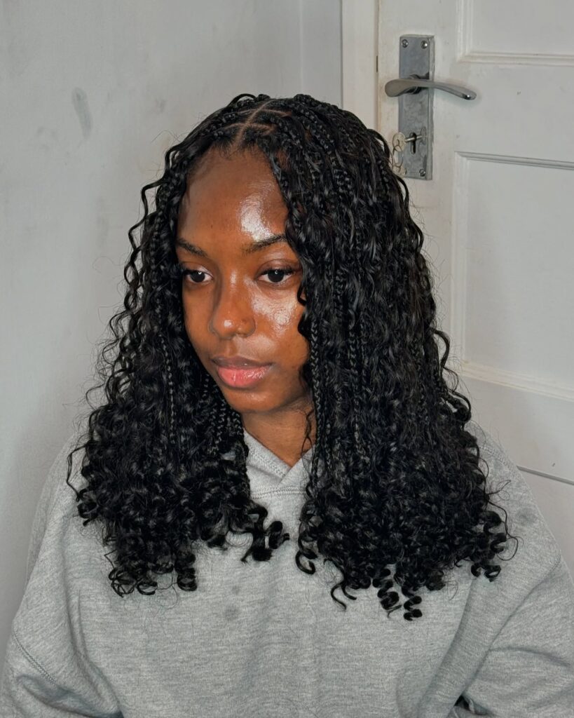 Short braided hairstyle with a center part and soft curly texture throughout.