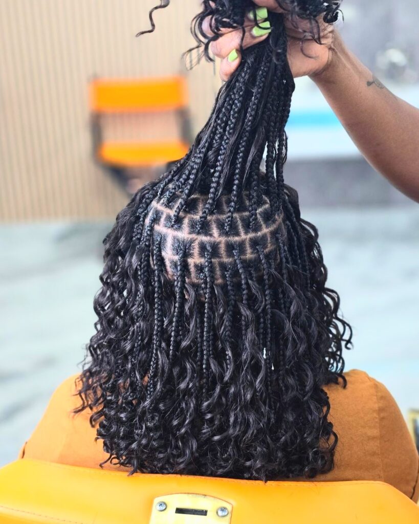 Knotless braids with visible square parts and curly ends styled on short hair.