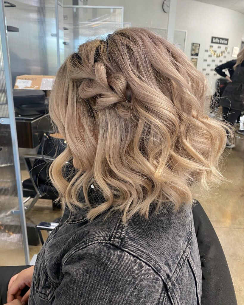 Short wavy blonde hair with a loose crown braid styled across the back.