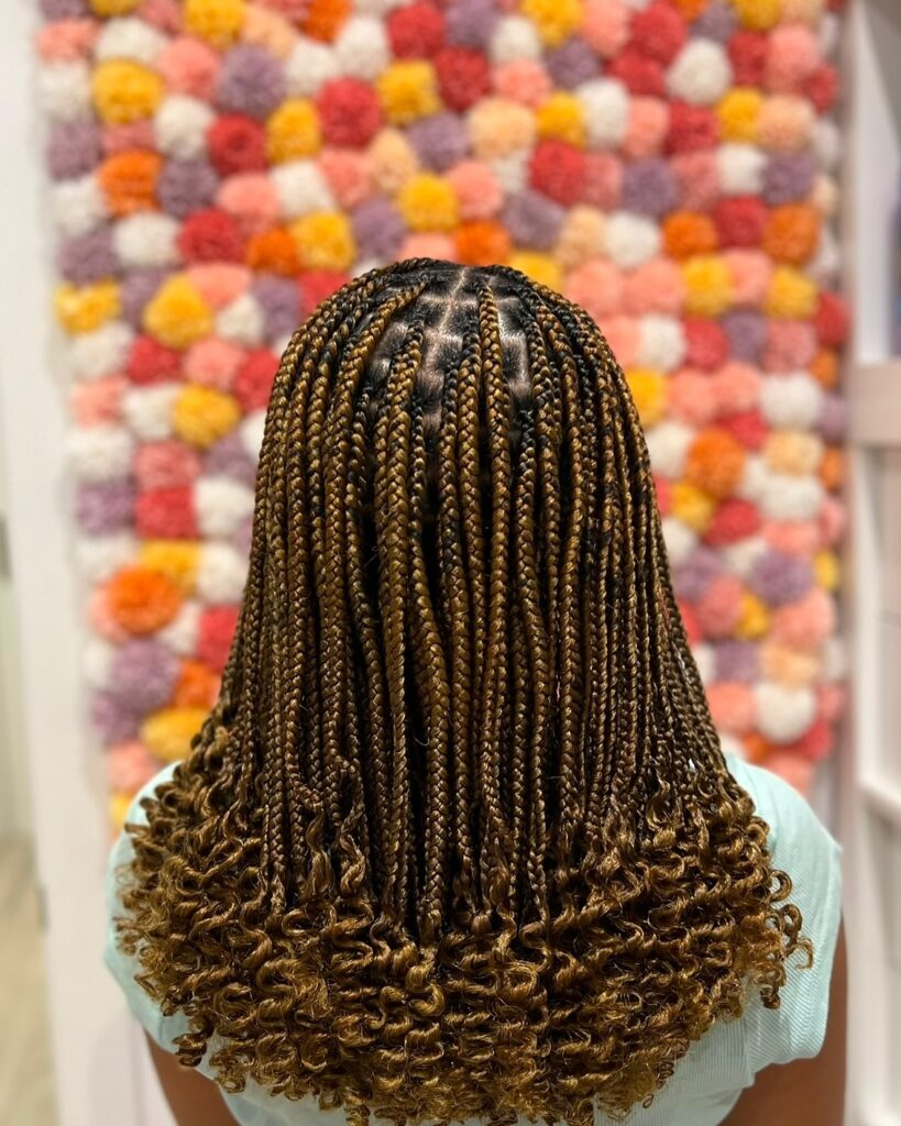 Golden brown box braids with defined parts and curly ends on a short length.