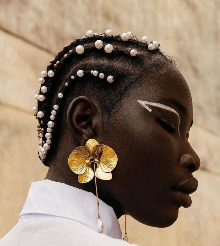 Short braided hairstyle with pearl accessories woven throughout the braids.