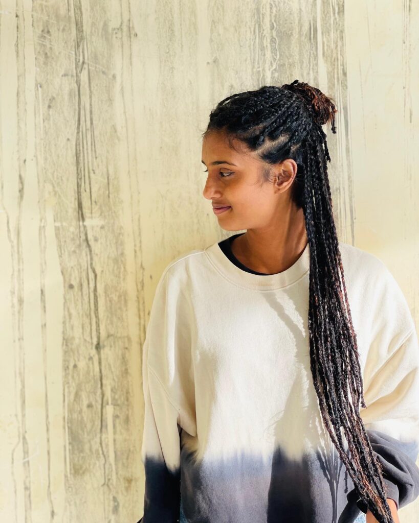 Long rope twist braids styled in a half up bun with loose twists hanging down.